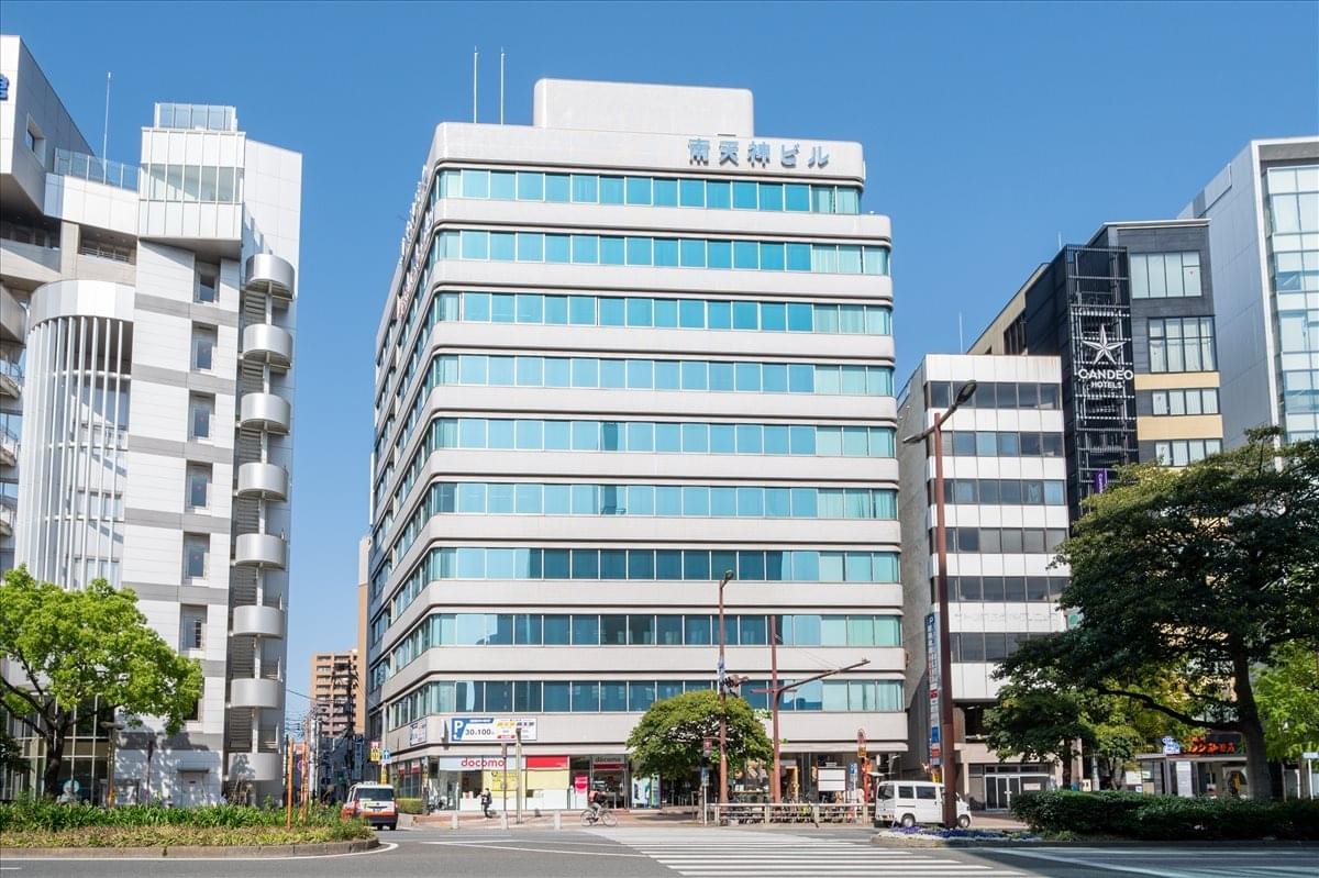 Exterior view of the white multi-story Minami Tenjin Building under a clear blue sky.