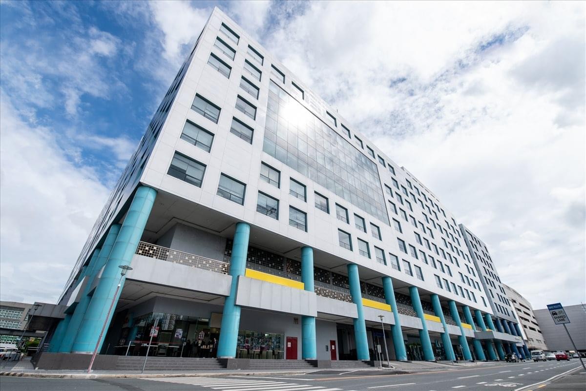 Low-angle exterior view of the modern white and blue One E-com Center Building.