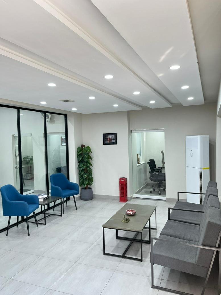 Bright reception waiting area with blue armchairs and grey sofa.