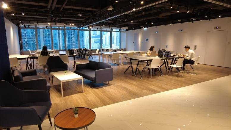 Spacious open-plan lounge with wood flooring, various seating areas, and a view of the skyline.