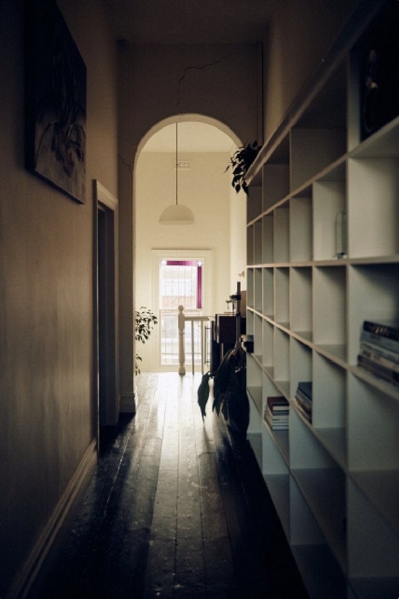 Narrow hallway with white shelving and a decorative archway.