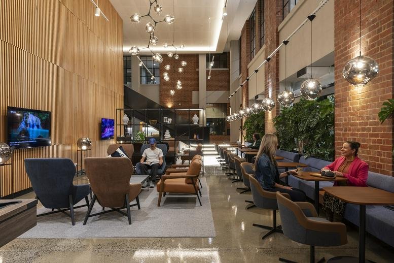 Spacious lobby at 425 Smith Street, Fitzroy, featuring high ceilings, warm wood paneling, and stylish lounge seating.