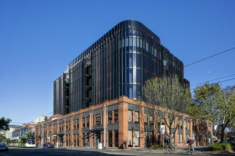 Modern multi-storey building exterior combining red brick and a dark glass facade.