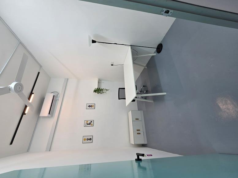 Well-lit office interior at Semangat Space with white walls, a desk, and modern light fixtures.