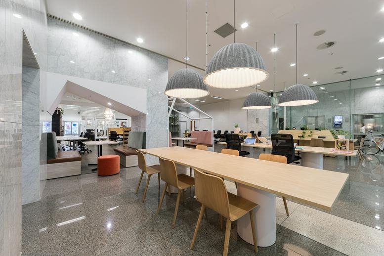 Spacious co-working lounge at 45 St Georges Terrace with long wooden tables and grey pendant lights.