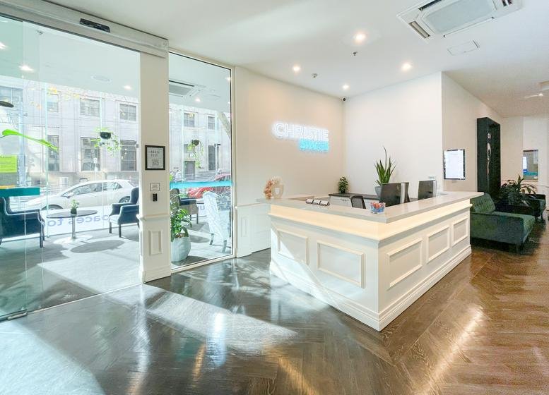 Bright, modern reception area at 454 Collins Street with a white paneled desk and large street-view windows.