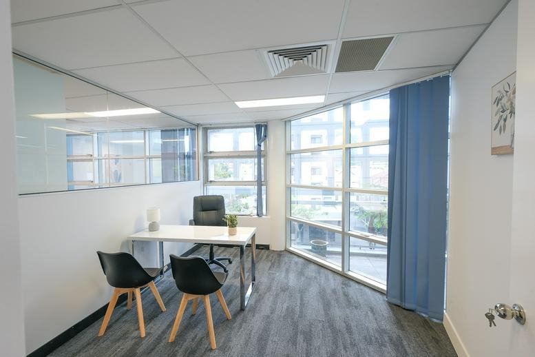 Bright private office at Business Hub Spring Hill with a white desk and two modern guest chairs.