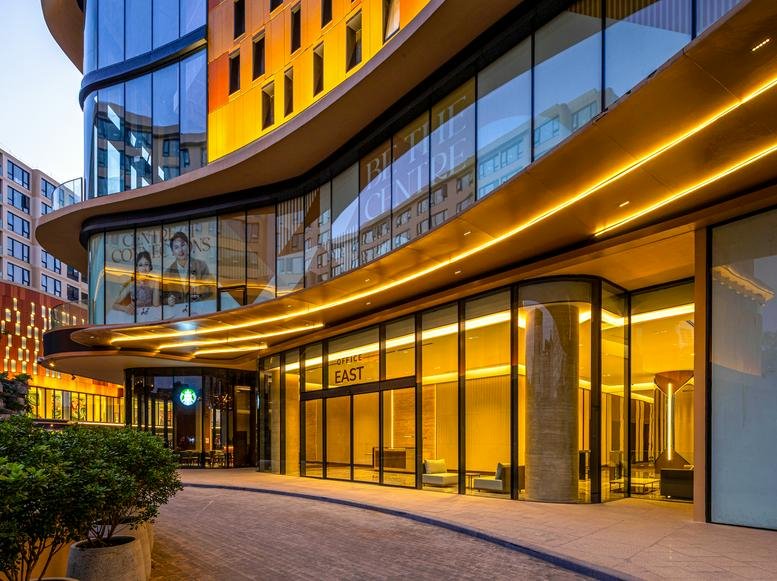 Curved exterior facade of the Hanoi Centre at 175 Nguyen Thai Hoc Street with warm evening lighting.