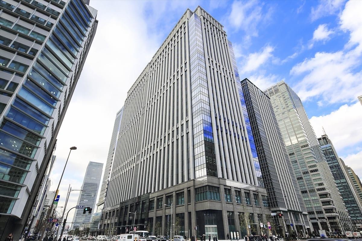 Low-angle exterior view of the glass and stone Tekko Building under a blue sky.