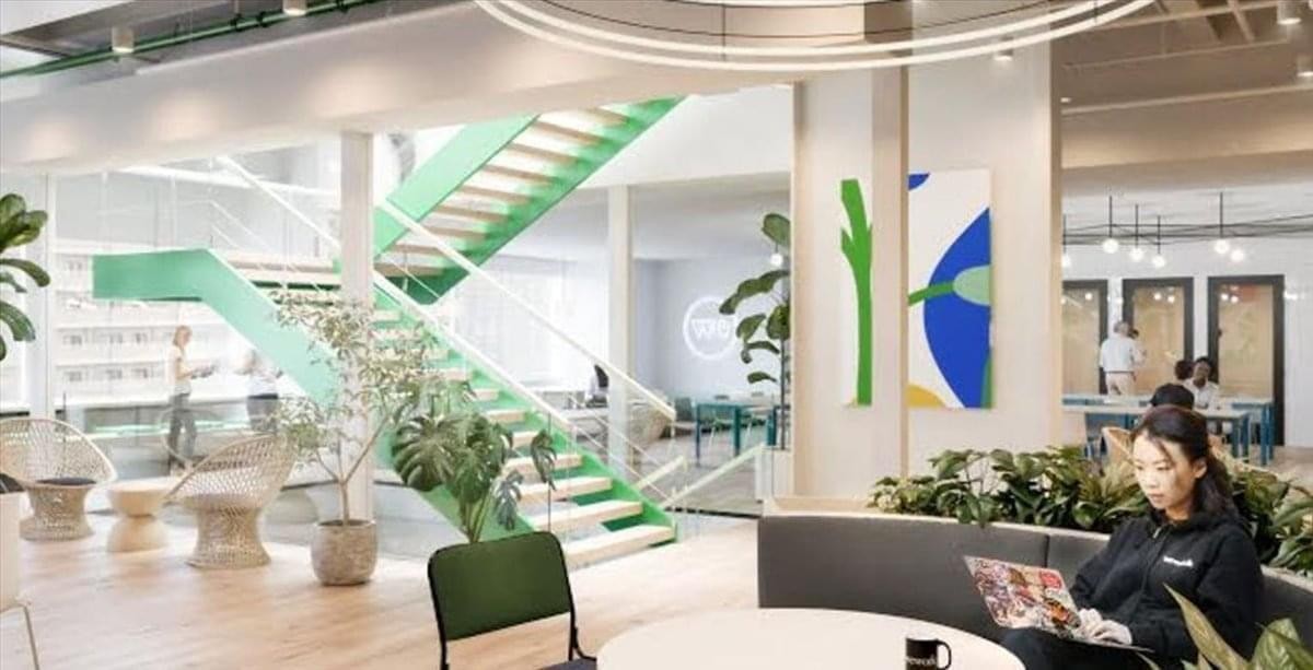 Spacious communal lounge at 5 Chome-1-60 Namba with a green staircase, plants, and natural light.