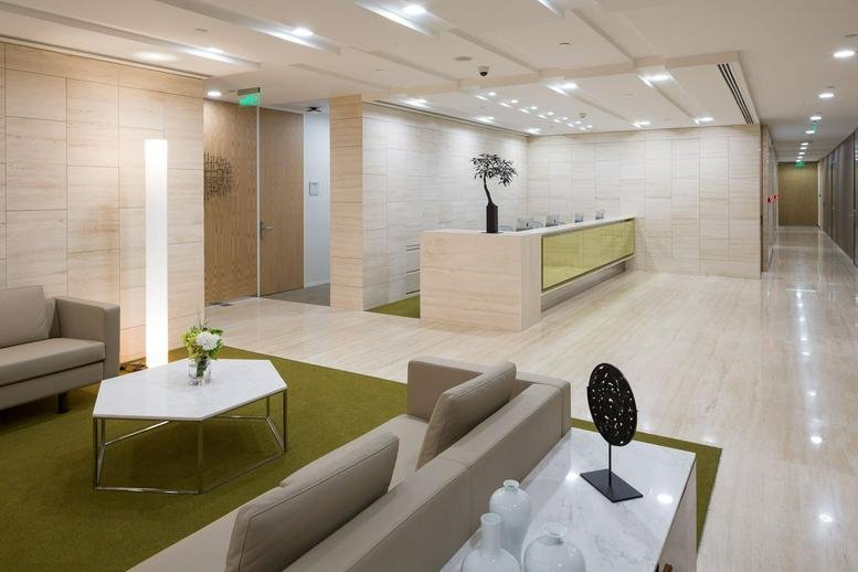 Modern reception area with marble finishes, a long service desk, and indoor plants.