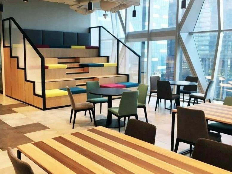 Spacious communal break area at UIC Building, 5 Shenton Way with tiered stadium seating and colorful cushions.