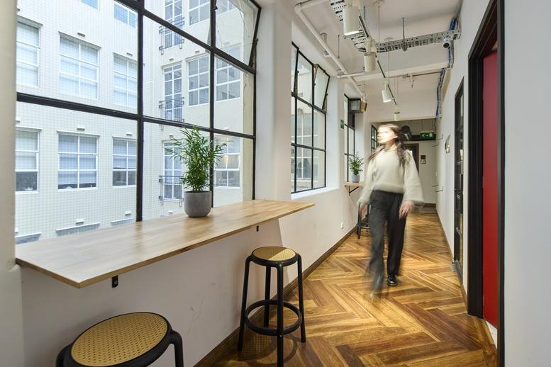 Bright hallway at WOTSO Geelong, 54 Malop Street, featuring a wooden bar table, bar stools, and large industrial windows.