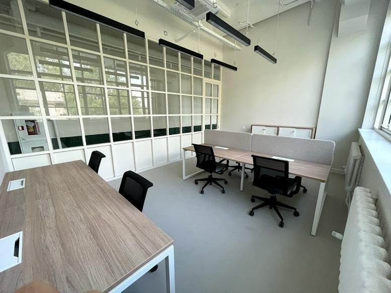 Spacious open-plan workspace at Fifty Four Coworking with modern desks and a large glass-paned feature wall.