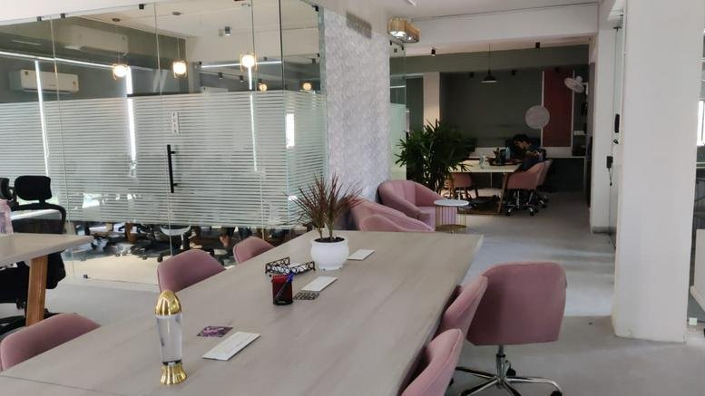 Spacious communal lounge featuring pink velvet chairs and a long wooden table.