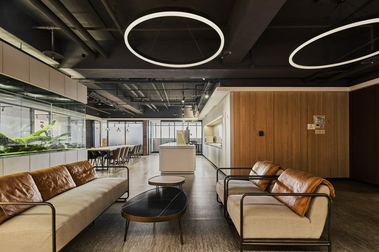 T3CO韻驊共享辦公 reception lounge with leather sofas, circular pendant lights, and wooden wall panels.