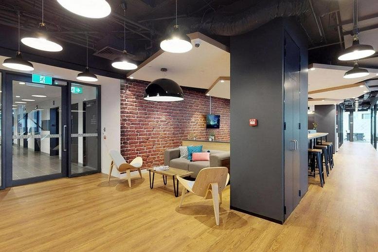 Vibrant communal hub with a mix of sofa seating, wooden floors, and a brick feature wall.