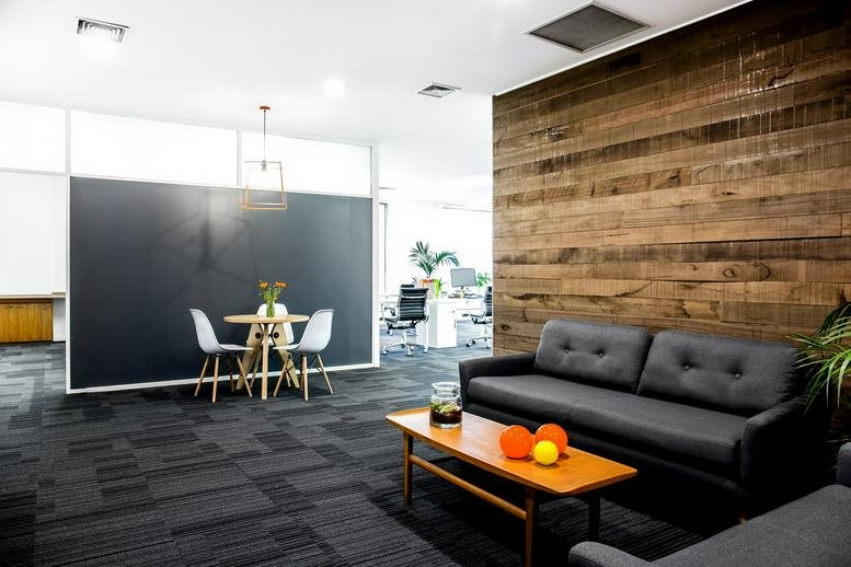 Modern lounge at 6 Riddell Pde, Elsternwick featuring a leather sofa and a rustic wood feature wall.