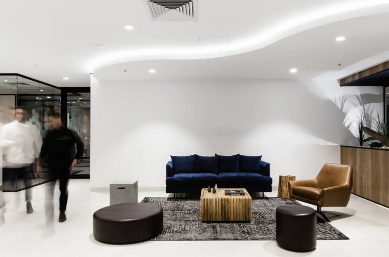 Modern lobby at 64, 66 Victor Crescent featuring a blue velvet sofa and curved illuminated ceiling.