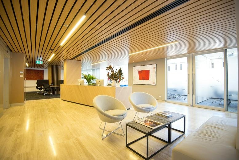 Modern reception area with warm wood-slatted ceilings and white designer armchairs.
