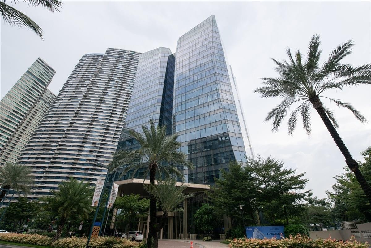 Low-angle exterior view of the modern glass-facade 8 Rockwell building surrounded by palm trees.
