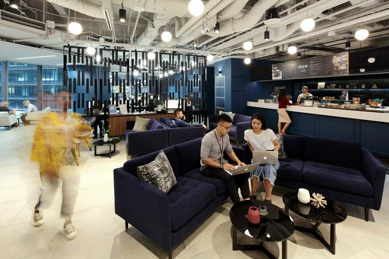 Spacious, modern coworking lounge at Marina One East Tower with navy blue velvet sofas and a stylish cafe area.