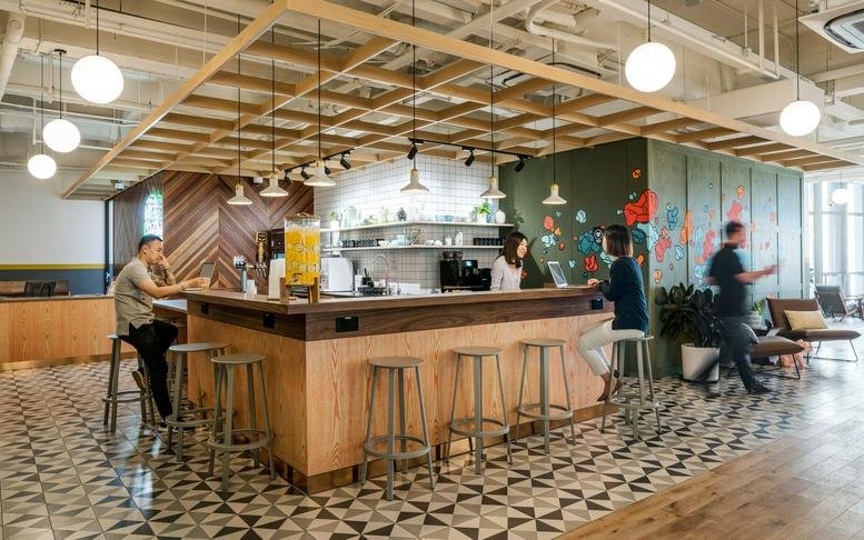 Spacious reception and café area with patterned floor tiles and a large wooden trellis ceiling feature.
