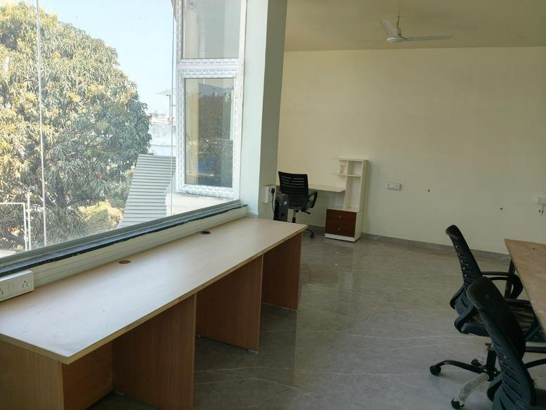 Spacious open-plan workspace at OrangeDesk Coworking with long wooden desks and large windows.