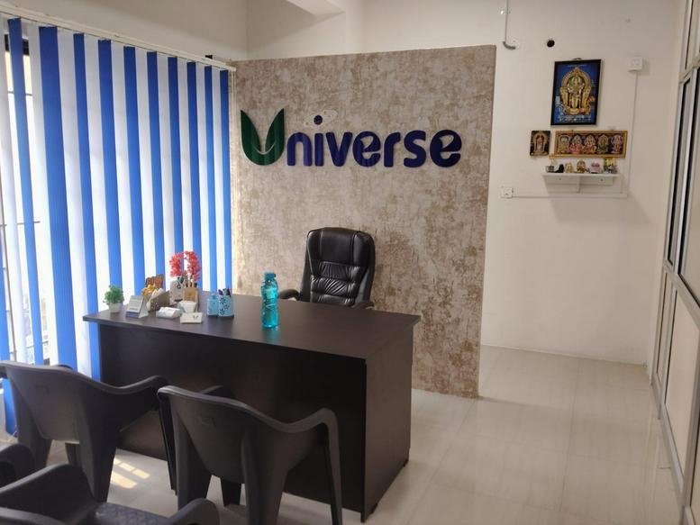 Reception area at Universe Coworks featuring a branded stone-texture feature wall and a dark wood desk.