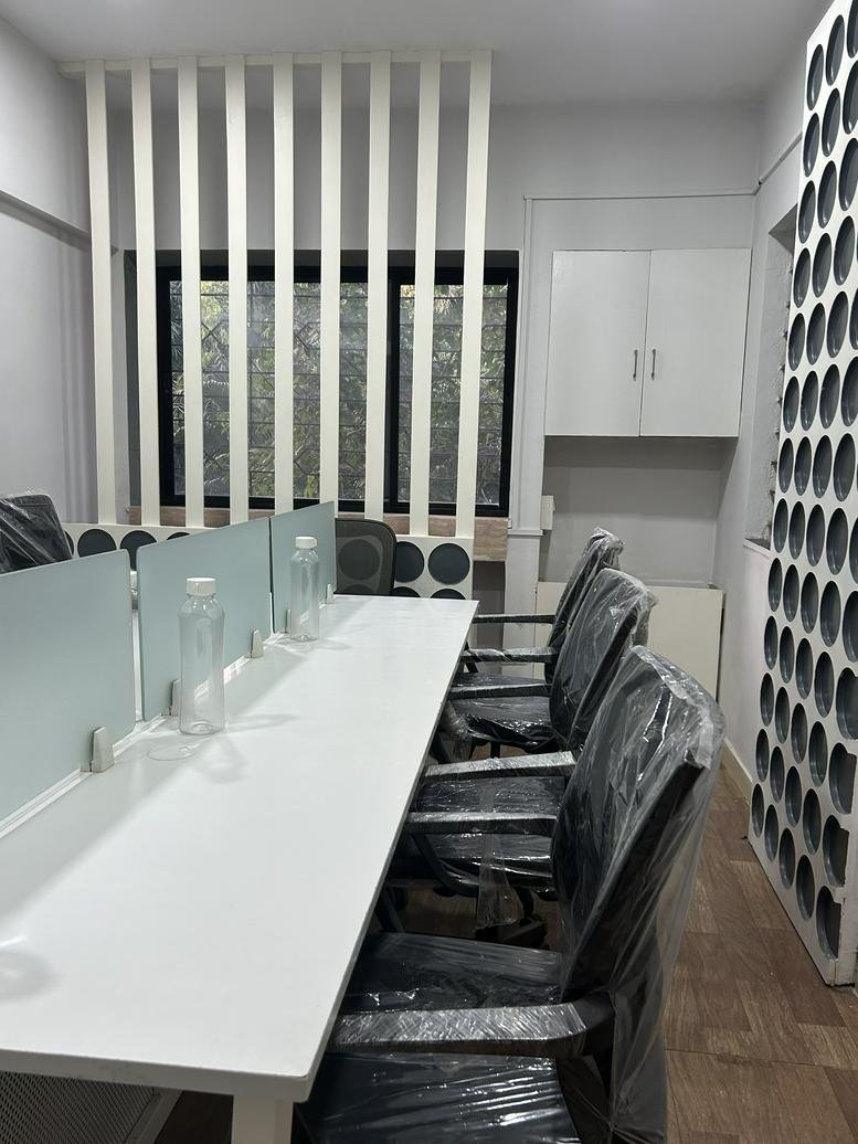 Modern open-plan office at Yash Coronet featuring white desks with glass dividers and ergonomic chairs.