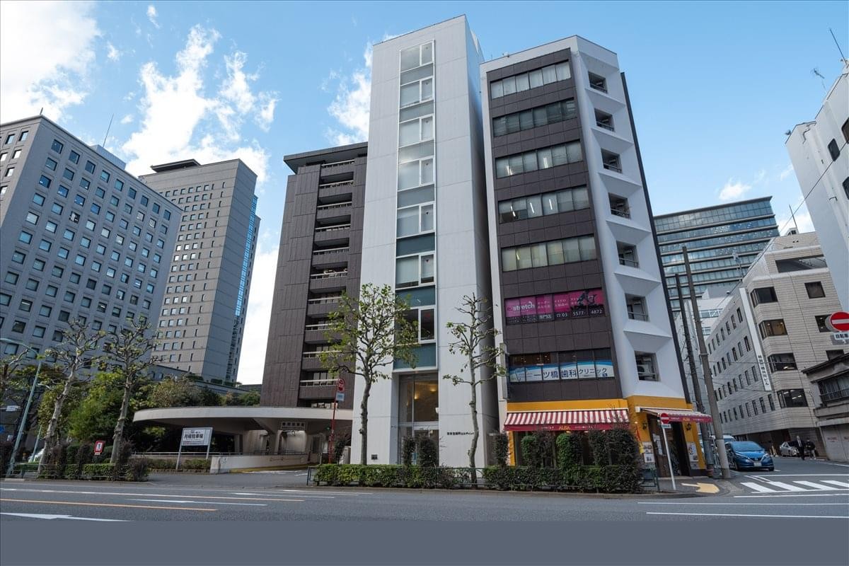 Exterior view of the multi-story Tokyodo Nishikicho Building under a bright sky.