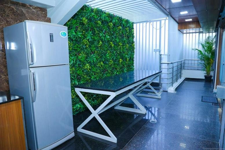 Modern breakroom area with a high black-top table and a large green living wall feature.