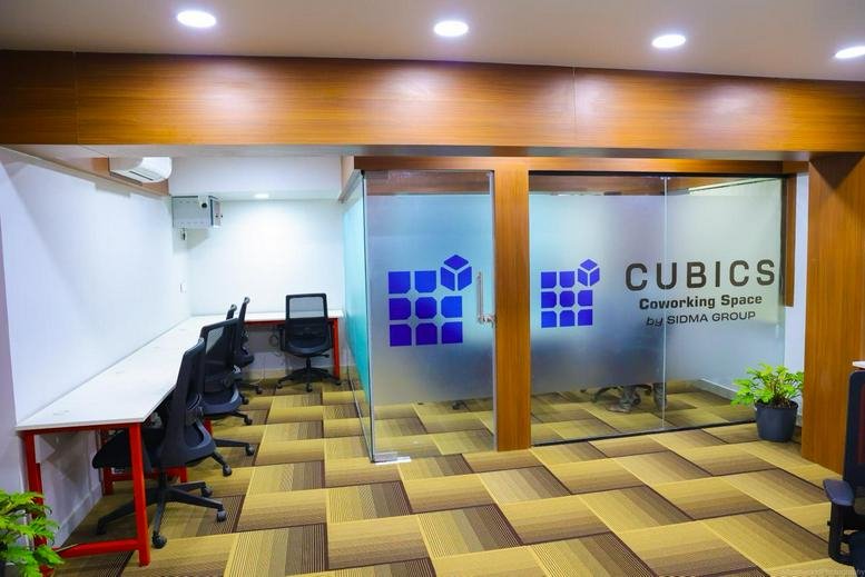 Entrance to Narendra Chambers featuring branded glass doors and an open-plan workspace with tan carpet.