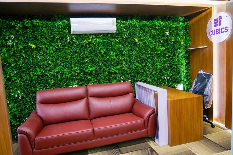 Reception area at Narendra Chambers featuring a red sofa against a vibrant green plant wall.