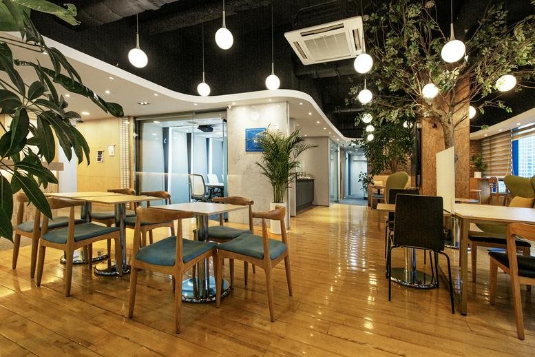 Vibrant communal cafe area with wooden flooring and tree-inspired decor.