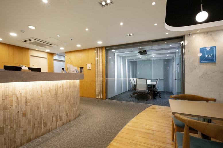 Bright reception area with a wood-paneled desk and glass meeting room.