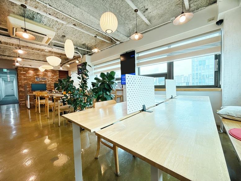 Spacious communal area at Aimhigh Tower with wooden tables and globe pendant lights.