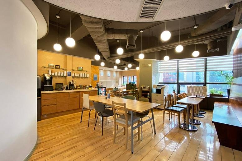 Spacious communal lounge and cafe area at Samwon Building with wooden floors and modern pendant lighting.