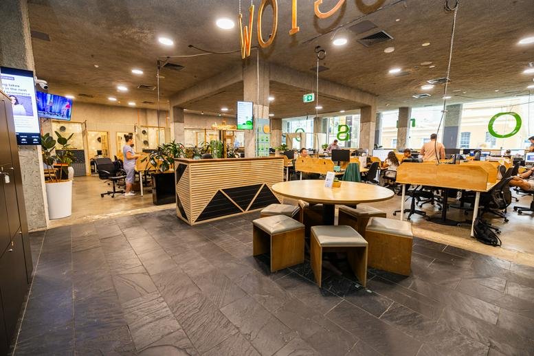 Spacious open-plan common area at 9-13 Bronte Road with round wooden tables and modern work pods.