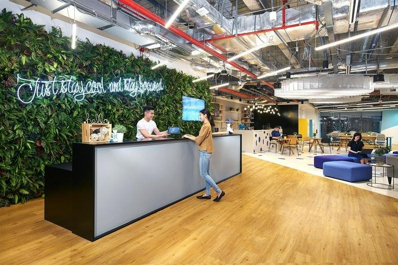 Reception area at Marina One West Tower featuring a lush green living wall and modern front desk.