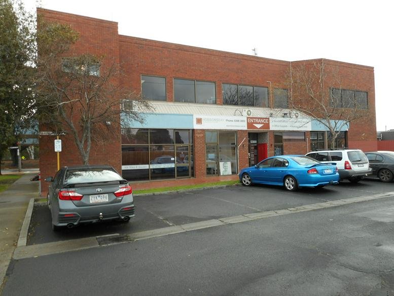 Exterior view of the brick building at 92 Railway Street with parking and a blue car out front.