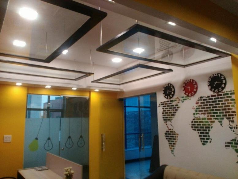 Modern reception lobby at A-74, A Block, Sec 63, Noida with world map wall art and geometric ceiling lights.