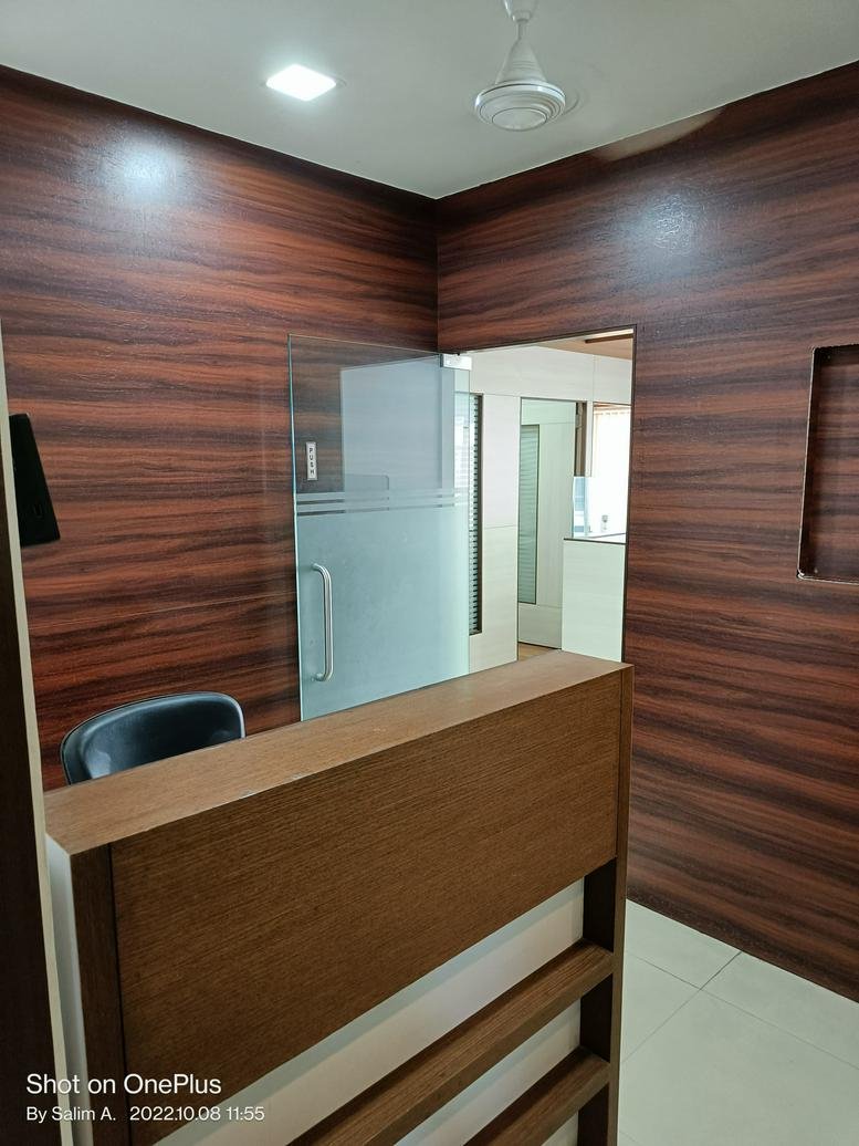 Reception area at Siddhi Vinayak Tower featuring wood-paneled walls and a glass entrance door.