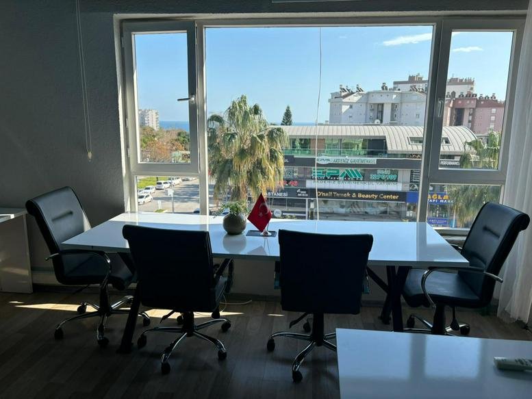 Spacious meeting room at Turan Ofis Lara with a long white table and floor-to-ceiling windows overlooking the city.