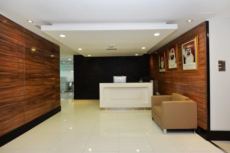 Reception area at ADNIC Building No. 403, Khalifa Street, with wood-paneled walls and a white marble desk.