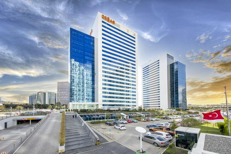 Exterior view of the glass-facade Akkom Office Park towers under a dramatic sky.