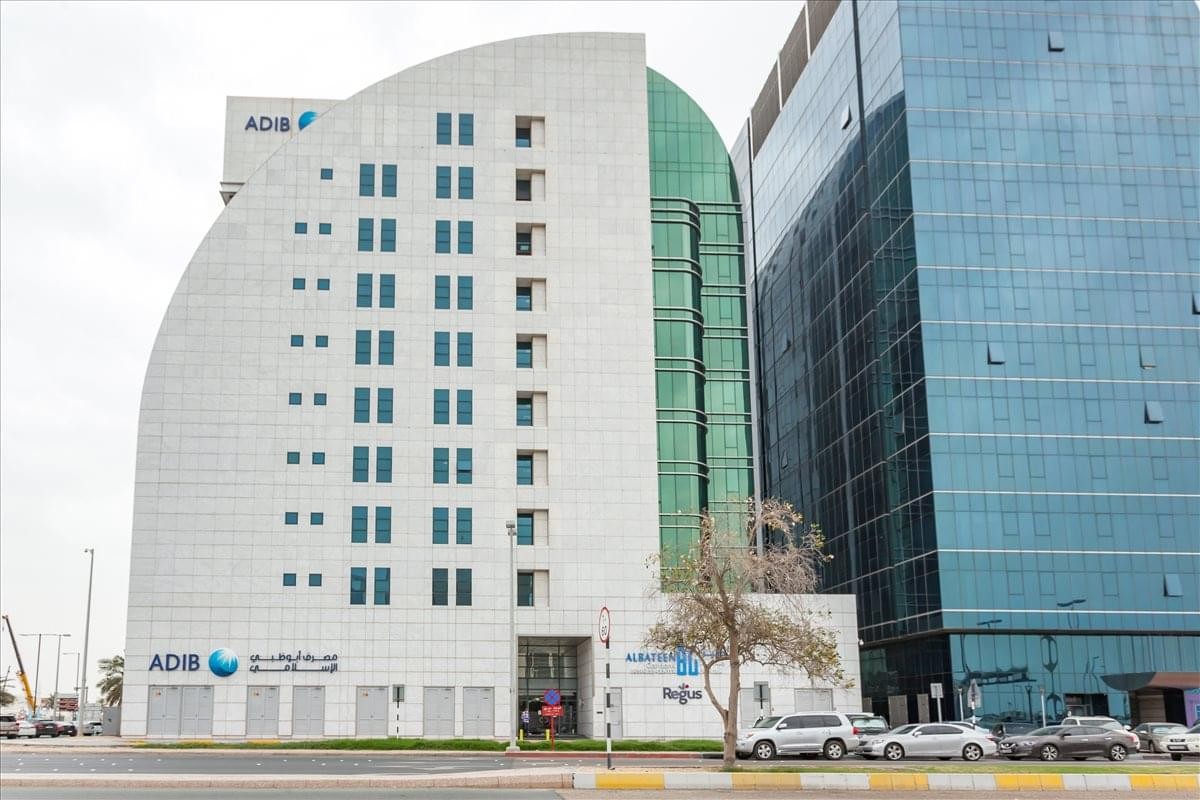 Exterior view of the Al Bateen tower c6 Bainunahi, ADIB Building with its curved white facade and green glass panels.