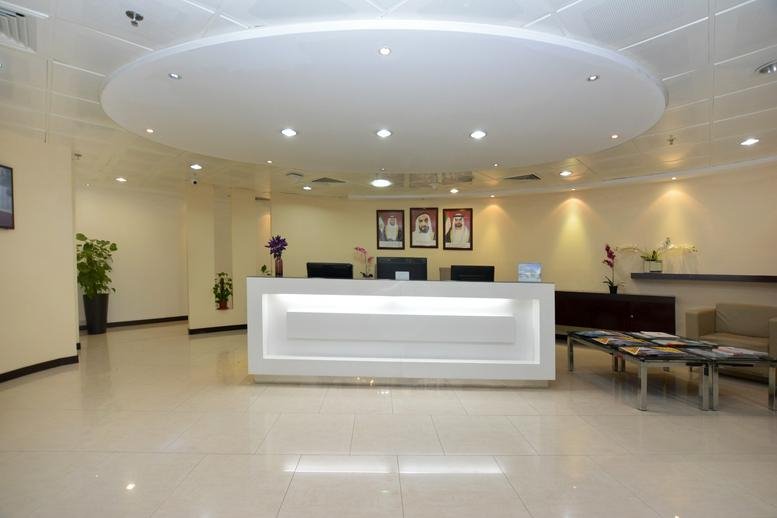 Spacious reception area at Al Ghaith Tower with a modern white desk and circular tray ceiling lighting.