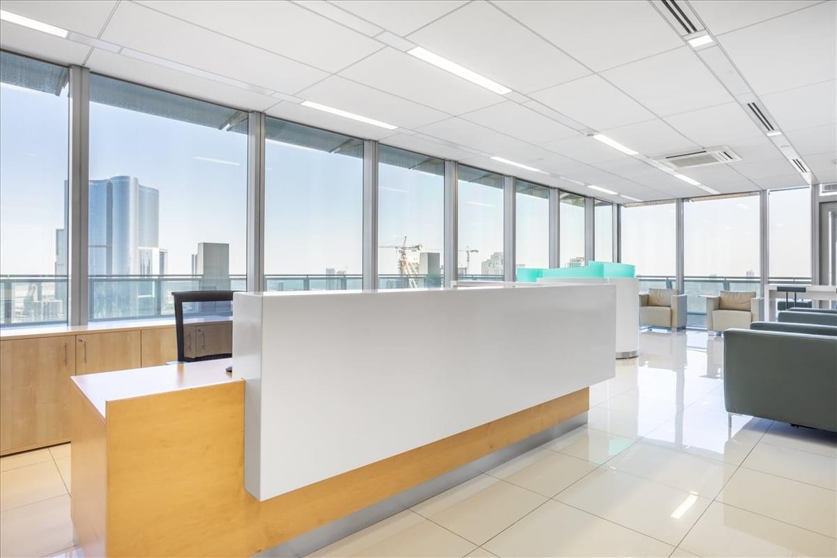 Lobby area featuring a sleek white and wood reception desk with city views.
