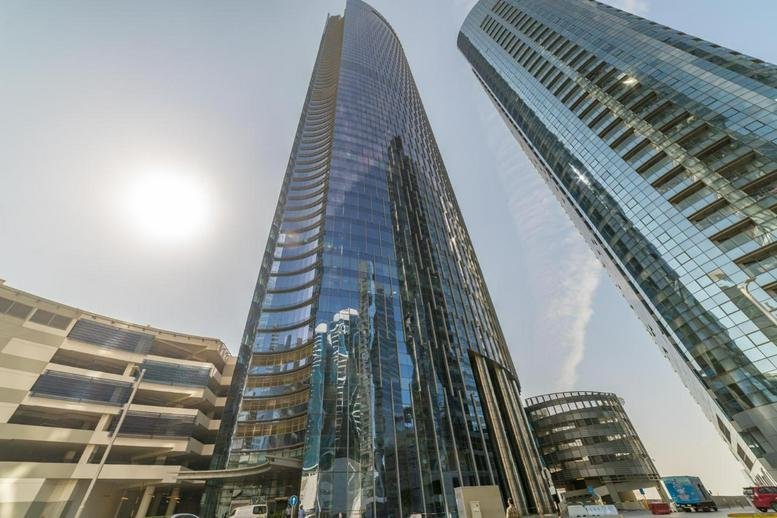 Exterior view of the glass-facade Addax Tower stretching into the clear sky.